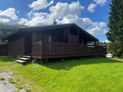 a house with a large deck on a grass field at Midttun Camping og Feriehytter in Vossestrand