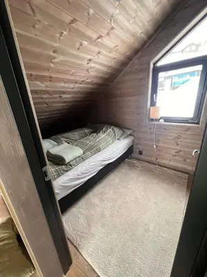 a small bed in a small room with a window at Rindabotn Fjelltun ski in-ski out in Sogndal