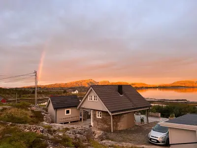 a rainbow in the sky over a house with a car at Sveggvika Atlantic Home in Averoy