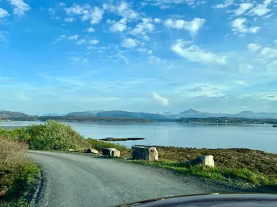 a road next to a body of water at Sveggvika Atlantic Home in Averoy