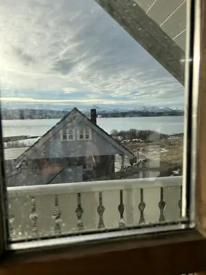 a window with a view of a house and water at Sveggvika Atlantic Home in Averoy