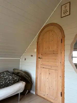 a room with a door and a bed in a attic at Sveggvika Atlantic Home in Averoy