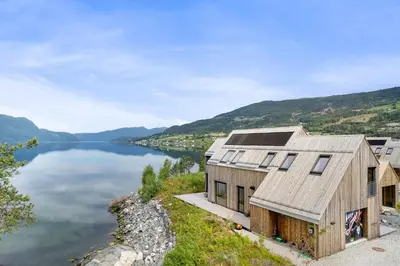 a house on the edge of a body of water at Modern house by the Fjord in Sandane, Nordfjord. in Sandane