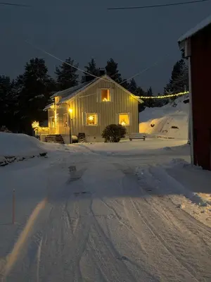 a house in the snow at night with lights at Sjarmerende og romslig bolig, omgitt av vakker natur in Molde