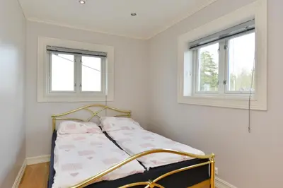 a bed in a white room with two windows at Elton Hotel in Raufoss