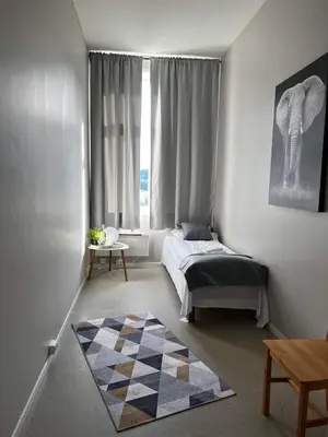 a bedroom with a bed and a checkered rug at Leirvik Vandrehjem in Leirvik
