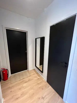 two black doors in a room with a wooden floor at Central Two Room Apartment! in Trondheim