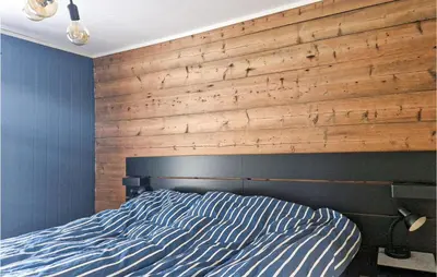 a bedroom with a bed with a wooden wall at 4 Bedroom Stunning Home In Fjæra in Fjæra