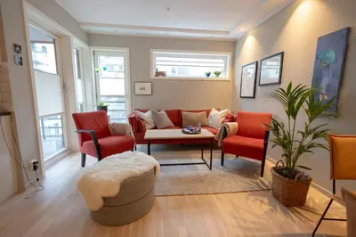 a living room with red chairs and a couch at Leilighet Damsgård , nær sentrum in Bergen