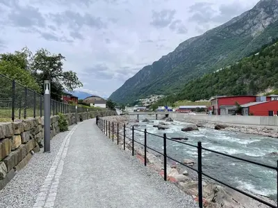 a path next to a river with mountains in the background at Leilighet i Odda sentrum in Odda