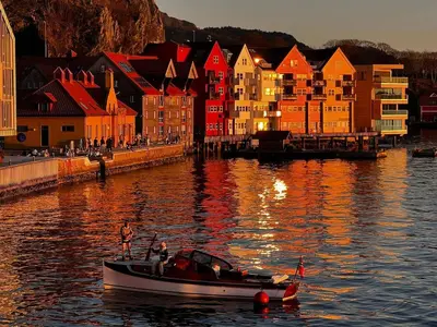 a boat in the water in front of a city at Central Seafront Apartments with Parking and Self Check-In! in Bergen