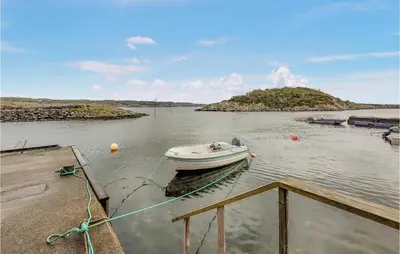 a boat is tied to a dock in the water at 3 Bedroom Lovely Home In Stolmen