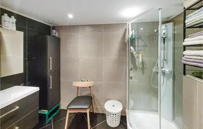 a bathroom with a shower and a chair and a sink at Nice Home In Bremnes With Wifi in Bremnes