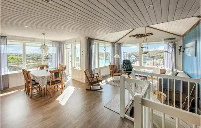 a dining room and living room with a table and chairs at Nice Home In Bremnes With Wifi in Bremnes