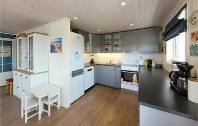 a kitchen with white cabinets and a black counter top at Nice Home In Bremnes With Wifi in Bremnes