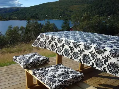 a table and two stools on a deck with a view of a lake at Panoramahytte in Norheimsund