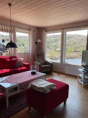 a living room with red furniture and large windows at Panoramahytte in Norheimsund