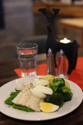 a plate of food with broccoli and eggs on a table at Hordatun Apartments in Røldal