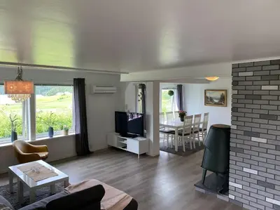 a living room with a couch and a tv at Feriehus i landlige område med nydelig utsikt in Leirvik