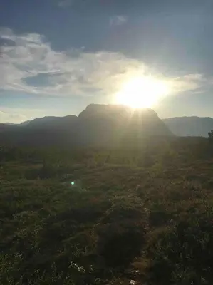 a view of the sun shining on a mountain at The Olav-house from 1840, at farm Ellingbø in Vang I Valdres