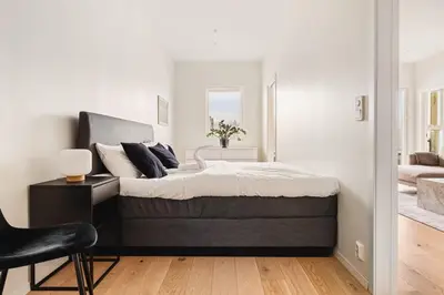 a bedroom with a large bed and a chair at Dinbnb Apartments I Luxury with Views l Large Balcony in Bergen