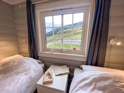 a bedroom with two beds and a window with a book at Chalet Krampehaugen by Interhome in Utvik