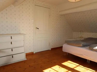 a bedroom with a bed and a dresser and a door at Holiday Home Sjøhytta by Interhome in Bekkjarvik