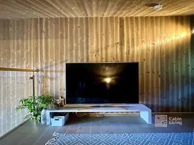 a large flat screen tv on a wooden wall at Sjusjøen ski in out, ski storage, Wifi, grill & fireplace, modern apartment! in Sjusjøen