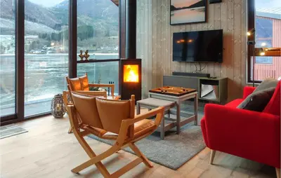 a living room with a fireplace and a table and chairs at Nice Home In Straumgjerde in Riksem