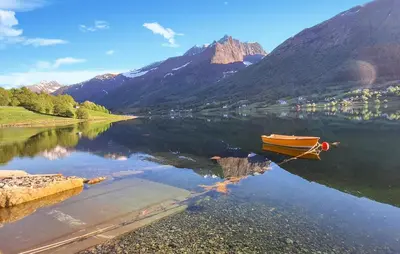 a boat on a lake with mountains in the background at Nice Home In Straumgjerde in Riksem