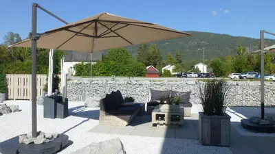 a patio with a couch and an umbrella at Løvheim Gjestehus in Sauland