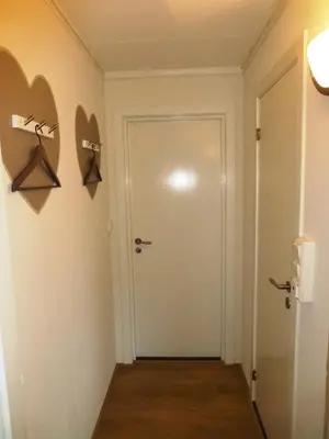 a hallway with a door and hangers on the wall at Løvheim Gjestehus in Sauland