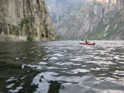 a person in a red kayak in the water at Sæbø Camping in Eidfjord
