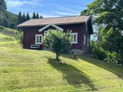 a small house on a hill with a tree in front of it at « SoFly Cottage », le charme pur in Noresund