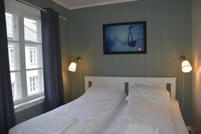 a bedroom with a white bed with two windows at Nedre Stensgården in Røros