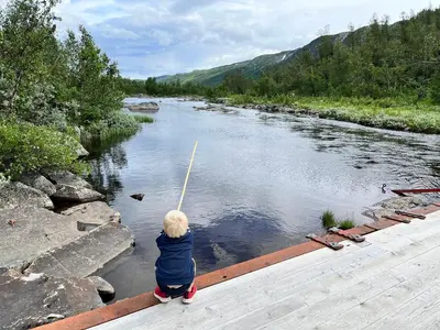 a little boy standing on a bridge holding a fishing pole at River view in Hovet