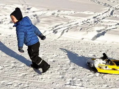 a boy standing next to a snowmobile in the snow at 5 star holiday home in Hemsedal-By Traum in Hemsedal