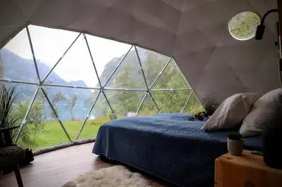 a bed in a tent with a large glass window at Olden Glamping - One with nature in Stryn
