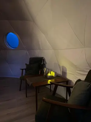 a room with tables and chairs and a wall with a blue light at Olden Glamping - One with nature in Stryn