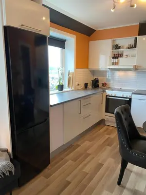 a kitchen with a black refrigerator and a chair at Leilighet med sydvendt balkong in Ålesund