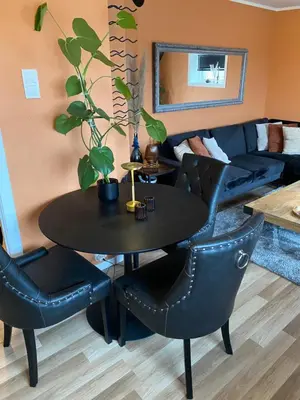 a table and chairs in a living room with a couch at Leilighet med sydvendt balkong in Ålesund