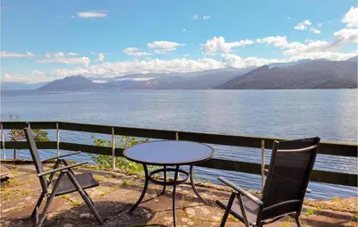 a table and chairs on a balcony overlooking a lake at Amazing Home In Tørvikbygd With Wifi in Tyrvikbygd
