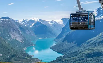 a gondola flying over a lake in the mountains at Mountain & Fjord View Apartment in Stryn