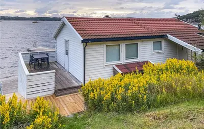 a house on a wooden deck next to a body of water at Stunning Home In Fitjar With Wifi in Fitjar