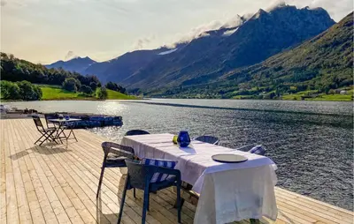 a table and chairs on a dock next to a lake at 2 Bedroom Cozy Home In Straumgjerde in Riksem