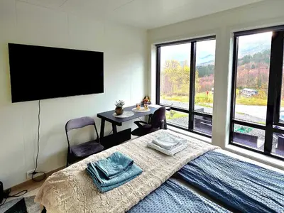 a bedroom with a bed with a table and a flat screen tv at Panorama view in Stranda