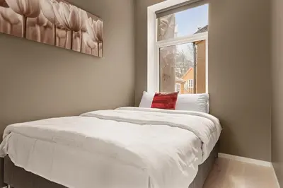 a bed in a room with a window at Dinbnb Apartments I New 2023 I 600m to Bryggen in Bergen