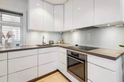 a white kitchen with white cabinets and a sink at Dinbnb Homes I Historical 1850 House in Bergen