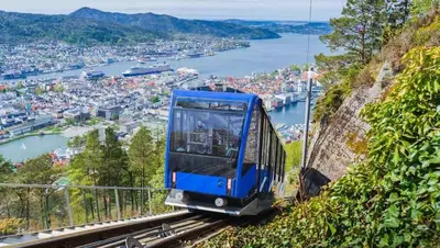 a blue tram on a mountain overlooking a city at Dinbnb Homes I Historical 1850 House in Bergen