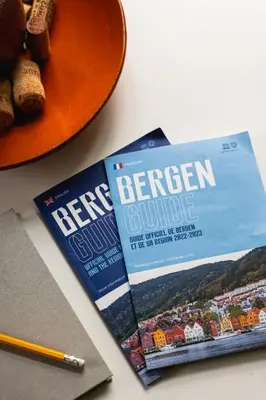 a book sitting on a table next to a pen and a plate at Dinbnb Apartments I New 2021 I SONOS and SMART TV in Bergen
